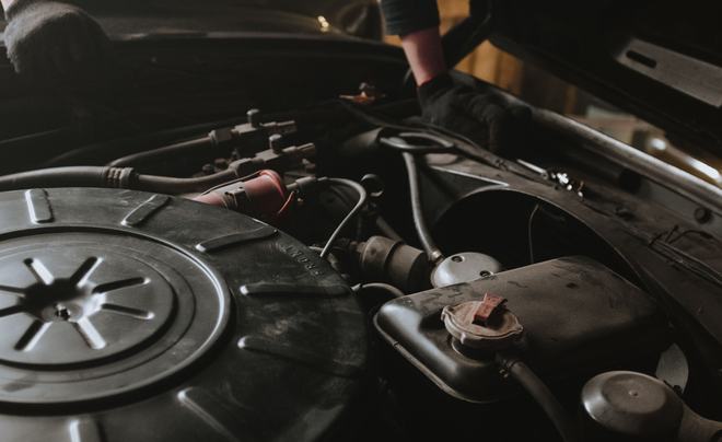 Mechanic working under a car bonnet for battery replacement